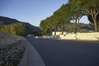 a young child is skateboarding along a wall in the middle of the road in the day