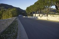 a young child is skateboarding along a wall in the middle of the road in the day