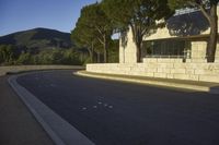 a young child is skateboarding along a wall in the middle of the road in the day