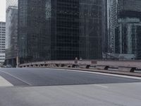 a man riding his skateboard on the street between large buildings in a city with a woman on a bench