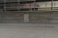 a man riding a skateboard through a cement covered parking lot under a building on a city street