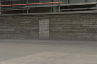 a man riding a skateboard through a cement covered parking lot under a building on a city street