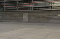 a man riding a skateboard through a cement covered parking lot under a building on a city street