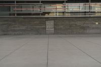 a man riding a skateboard through a cement covered parking lot under a building on a city street