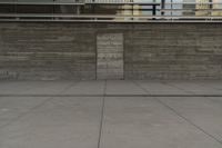 a man riding a skateboard through a cement covered parking lot under a building on a city street