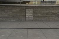 a man riding a skateboard through a cement covered parking lot under a building on a city street