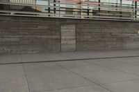 a man riding a skateboard through a cement covered parking lot under a building on a city street