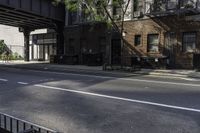 a man riding a skateboard down a sidewalk near a street under an overpass