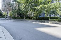 a car driving down an empty street lined with tall buildings and trees in the background