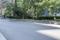 a car driving down an empty street lined with tall buildings and trees in the background