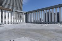 a person is skateboarding on the concrete roof of a building, with tall buildings behind them