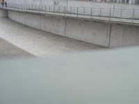 the skateboarder is skateboarding down the concrete walkways near a riverbank