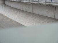 the skateboarder is skateboarding down the concrete walkways near a riverbank