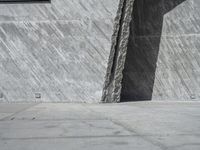 a person skateboarding in front of a wall that is partially made out of concrete