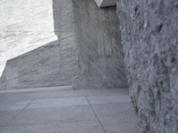 a young man skateboarding near a large concrete wall and stairs in front of a blue sky