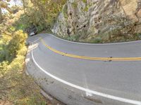 a person skateboarding down a curvy road in the mountains at sunset time