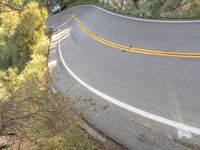 a person skateboarding down a curvy road in the mountains at sunset time