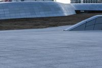 a skateboarder rides down a ramp in front of a building and other tall buildings