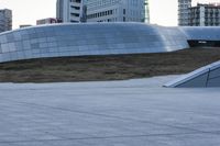 a skateboarder rides down a ramp in front of a building and other tall buildings