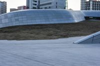 a skateboarder rides down a ramp in front of a building and other tall buildings