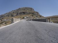 a man on a skateboard riding down a steep road next to a mountain,