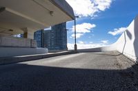 the person on the skateboard rides down the ramp near tall buildings while the sun shines brightly behind