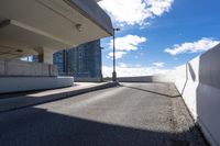 the person on the skateboard rides down the ramp near tall buildings while the sun shines brightly behind