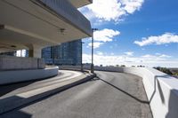 the person on the skateboard rides down the ramp near tall buildings while the sun shines brightly behind