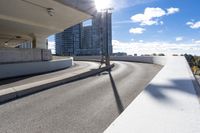 the person on the skateboard rides down the ramp near tall buildings while the sun shines brightly behind