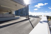 the person on the skateboard rides down the ramp near tall buildings while the sun shines brightly behind