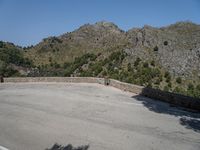 a person riding a skate board next to a hill of rocks with trees in the background