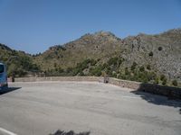 a person riding a skate board next to a hill of rocks with trees in the background