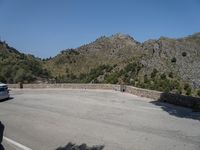 a person riding a skate board next to a hill of rocks with trees in the background