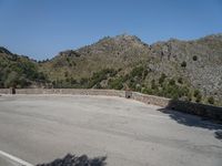 a person riding a skate board next to a hill of rocks with trees in the background