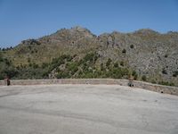 a person riding a skate board next to a hill of rocks with trees in the background