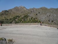 a person riding a skate board next to a hill of rocks with trees in the background