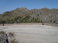 a person riding a skate board next to a hill of rocks with trees in the background