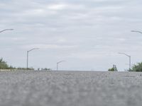 a person skateboarding across an empty open road with trees in the background at the bottom