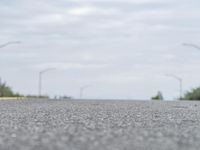 a person skateboarding across an empty open road with trees in the background at the bottom