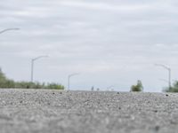 a person skateboarding across an empty open road with trees in the background at the bottom