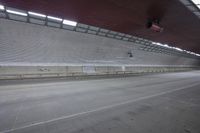 a man is on a skateboard riding down an empty street with a tunnel in the background