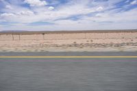 a man riding a skateboard down the side of a road in front of an empty plain