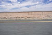 a man riding a skateboard down the side of a road in front of an empty plain