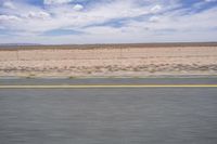 a man riding a skateboard down the side of a road in front of an empty plain