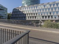 a skateboarder skates across an empty bridge with buildings on both sides in the background