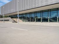 the man skateboards in front of an empty parking lot by a glass - clad building