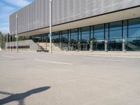 the man skateboards in front of an empty parking lot by a glass - clad building