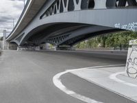 the skateboarder is skateboarding under a bridge with graffiti written underneath it,