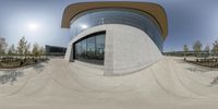 a skateboarder rides down a half pipe that sits outside of an architectured building