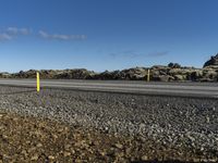 a person riding their skateboard in a parking lot near some rocky terrain and a yellow post